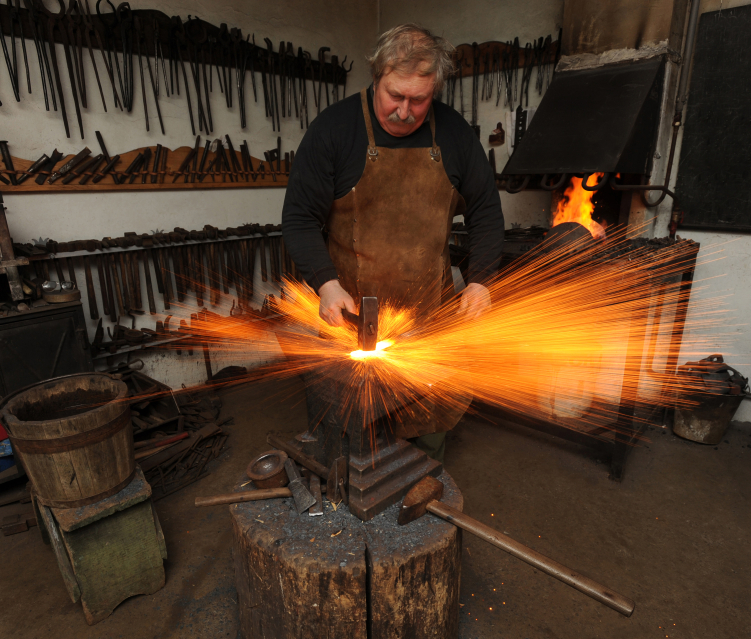 Blacksmith forging metal with sparks
