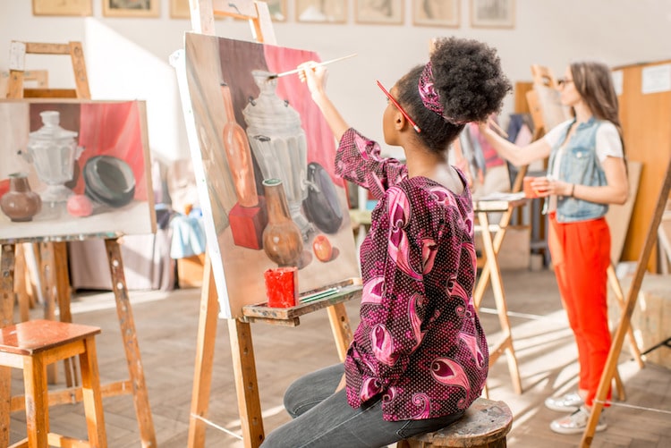 Artist painting at an easel in studio