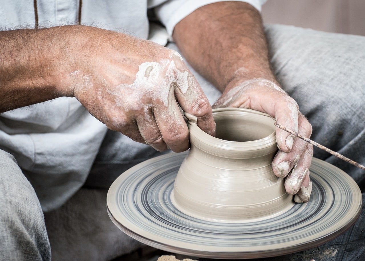 Hands shaping clay on a pottery wheel