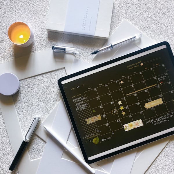 Digital planner displayed on tablet with stylus and stationery on a clean desk