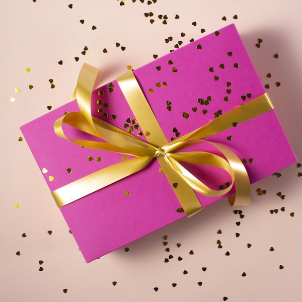 Beautifully wrapped gift box with gold ribbon and heart confetti